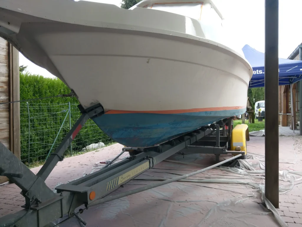 Coque bateau fibre de verre antifouling dégradé sur remorque avant décapage aérogommage Belgique